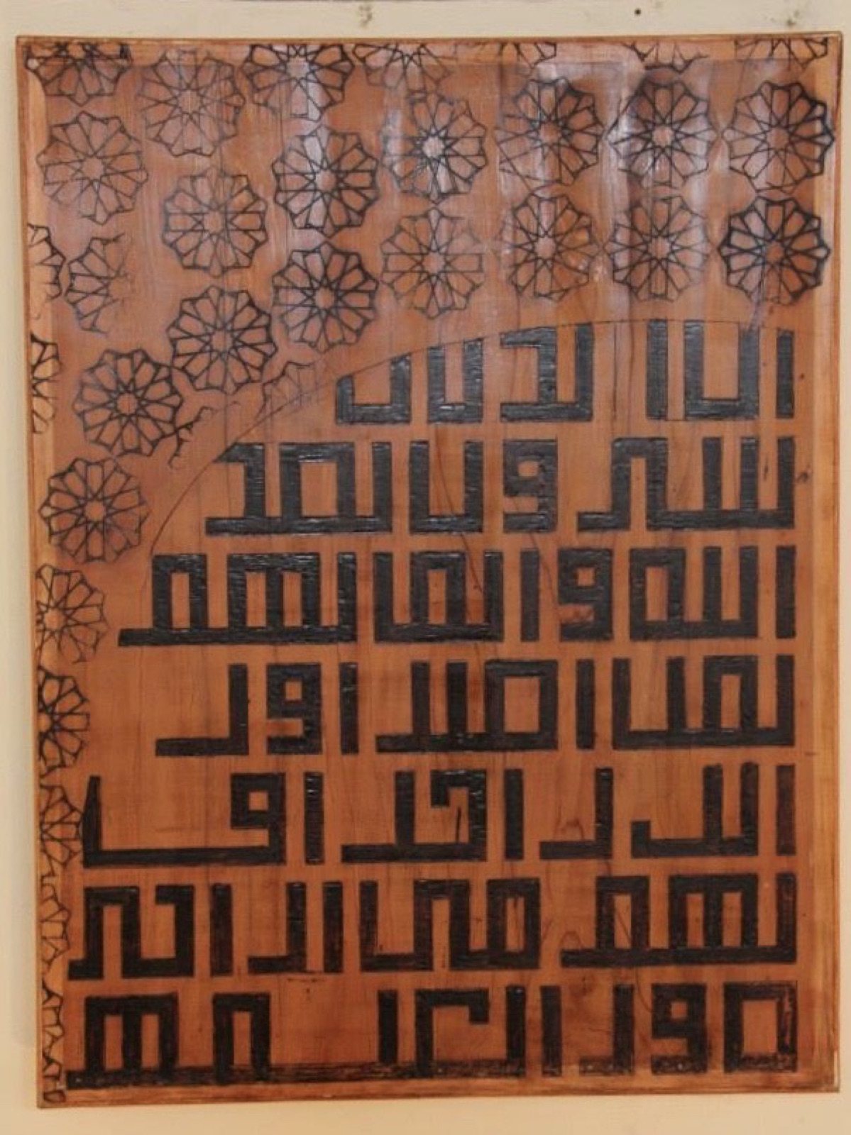 Kufic calligraphy set within an arch over a field of geometric florets