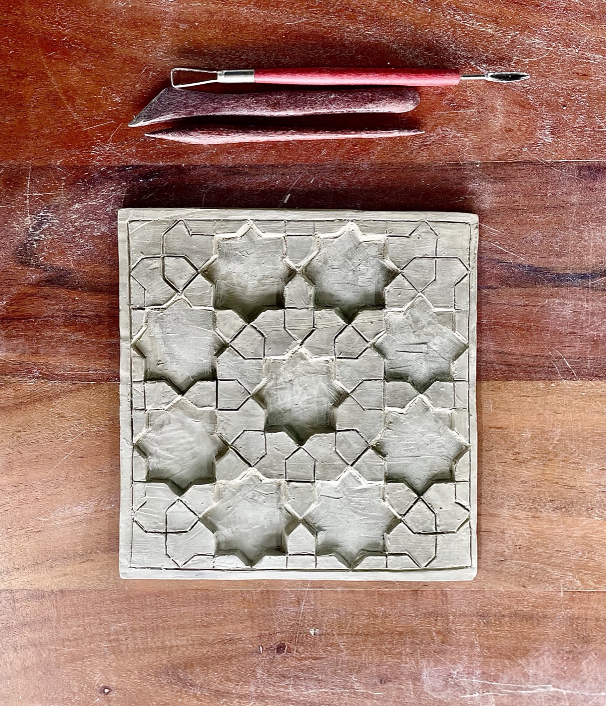 Grey clay tile carved with an interlocking eight-point star pattern